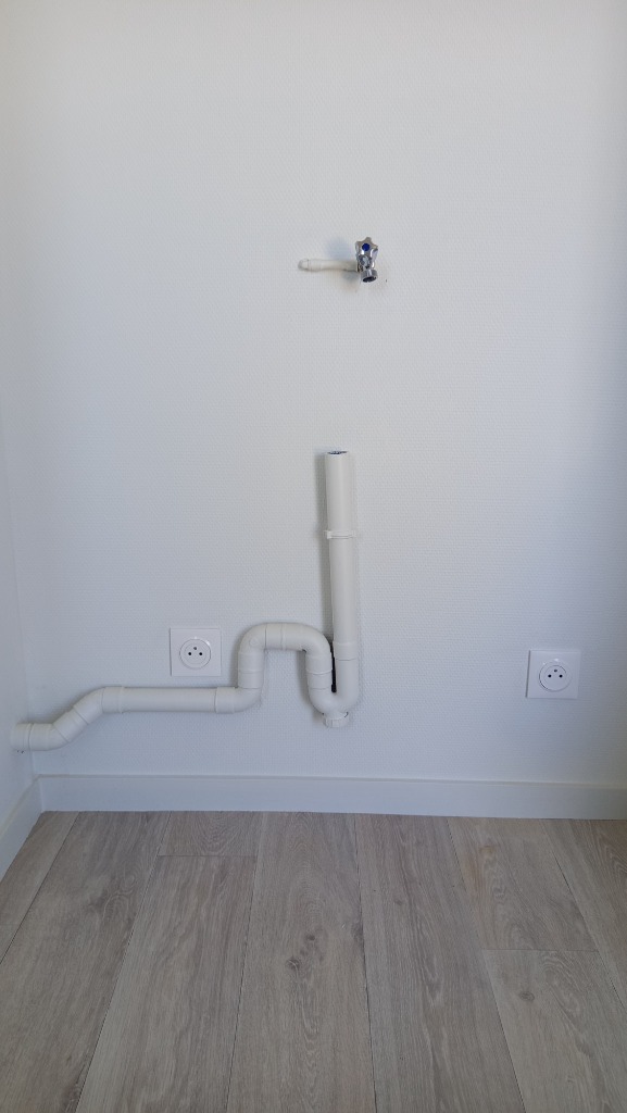 Création d'un réseau d'évacuation PVC blanc avec siphon anti-odeur et robinet d'arrivée d'eau pour machine à laver par un artisan plombier à Lyon